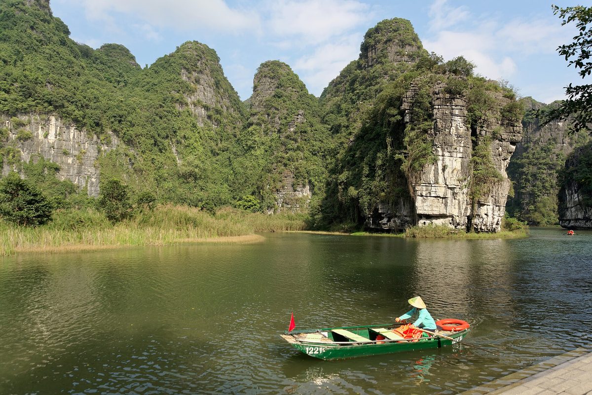 Limestone karsts and a sampan boat in Trang An, Ninh Binh